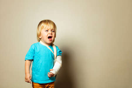 Screaming boy with broken hand in plaster cryの写真素材