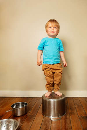 Toddler boy play with kitchenware stand on a panの写真素材