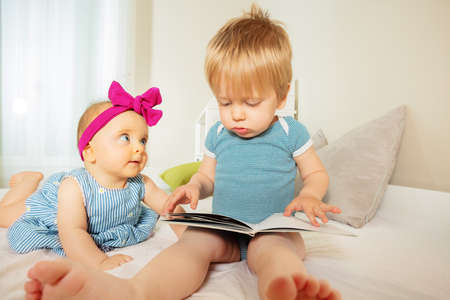 Baby boy read book to little infant girlの写真素材