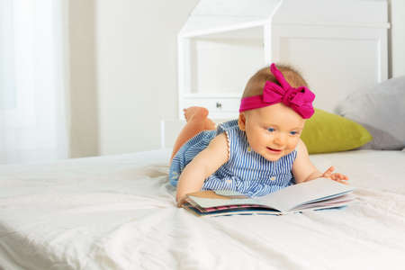 Portrait of little stylish baby girl read bookの写真素材