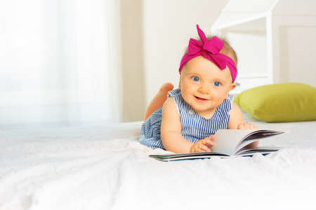 Portrait of stylish baby girl look through bookの写真素材