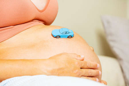 Toy car on big pregnant womans belly, close-upの写真素材