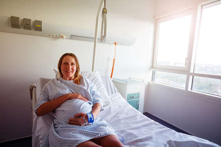 Smiling pregnant woman lay in hospital bedの写真素材