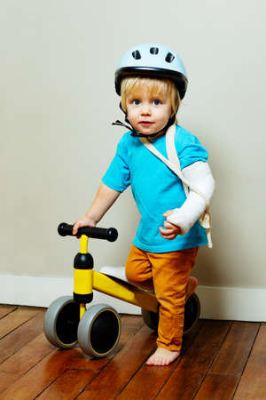 Boy with broken hand in plaster and little bicycleの写真素材