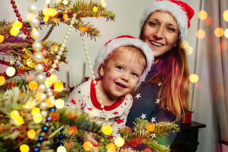 Happy little boy with mother near Christmas treeの写真素材
