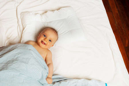 Laughing baby little girl in bed view from aboveの写真素材