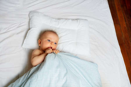 Portrait of the little baby girl lay in a bedの写真素材
