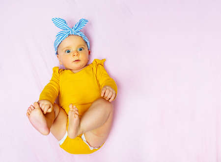 Baby girl lay in bed wear bow and look upの写真素材