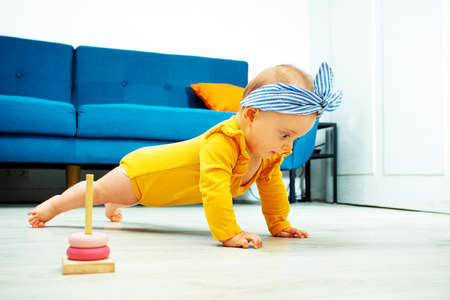 baby girl stand on legs and hands holding plankの写真素材