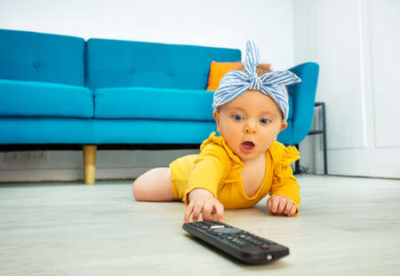 Little baby girl stretch hand reaching tv controlの写真素材