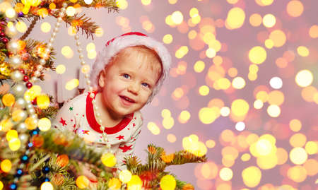 Cute toddler boy looking behind of Christmas treeの写真素材