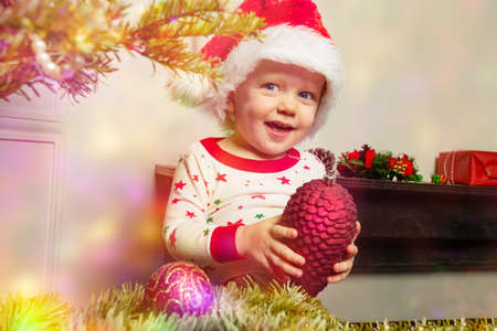 Happy toddler in Sant hat decorate Christmas treeの写真素材