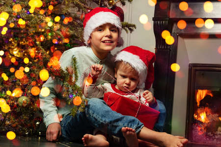 Brothers open Christmas presents near fireplaceの写真素材