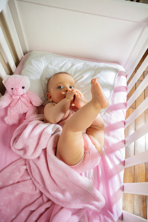Happy baby girl lay in pink bed smiling top viewの写真素材