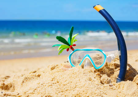 Scuba mask, tube on sand of sea beach with wavesの写真素材