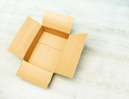 Empty open cardboard box on the parquet floorの写真素材
