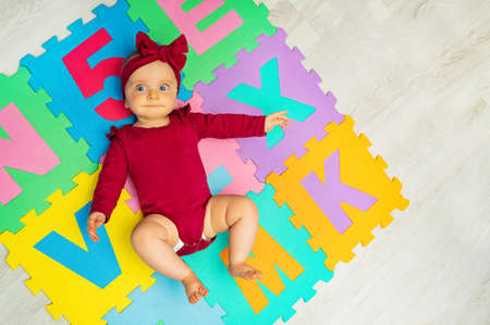 Little baby girl lay on the color ABC carpetの写真素材