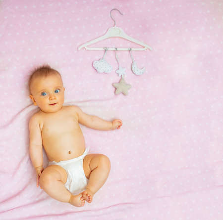 Cute baby girl and mobile toys on pink blanketの写真素材