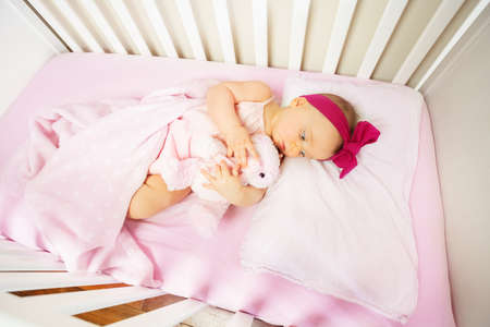 baby lay in crib bed with calm expression hug toyの写真素材