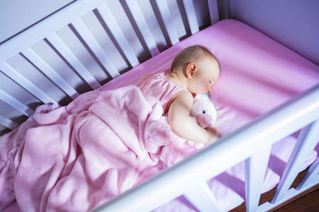 View from side of little baby girl sleep with toyの写真素材