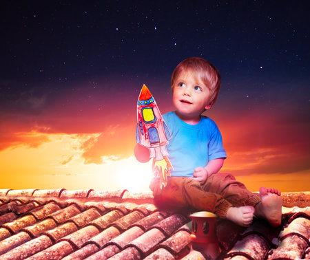 Baby boy play with paper rocket sitting on roofの写真素材