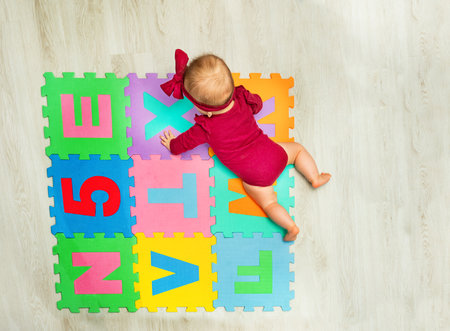 Happy baby girl creep on the carpet with lettersの写真素材