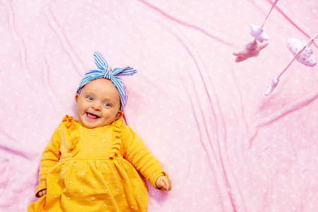 Laughing happy baby girl on pink blanket in crib