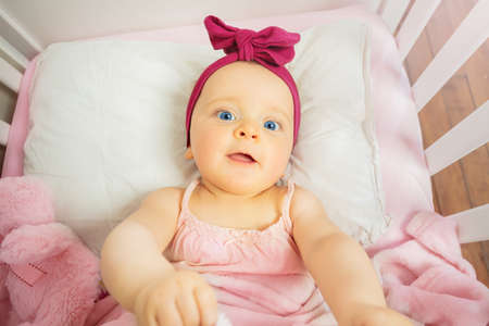 View from above of a little baby girl in pink bedの写真素材