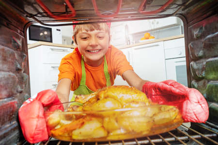 Happy smiling boy take fried chicken from ovenの写真素材