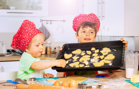 Boys put cookies on the tray prepare for bakingの写真素材