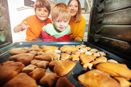 Curious and surprised boy check cookies in ovenの写真素材