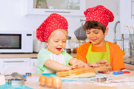 Two boys cook and bake cookies wearing chef hatの写真素材