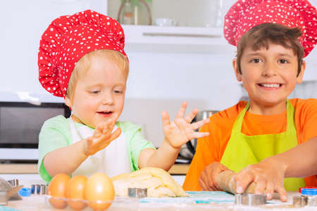 Happy toddler with brother prepare baking doughの写真素材