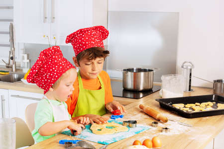 Little kids cut out forms from dough at kitchenの写真素材