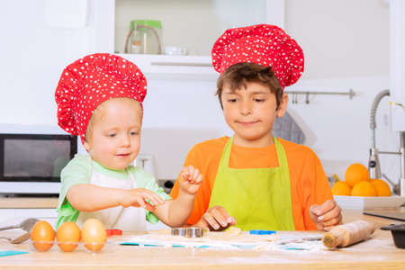 Two boys cutting dough out cookies in heart shapesの写真素材