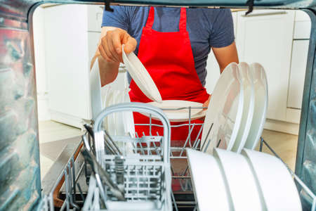 Man taking dishes and plates out of dishwasherの写真素材