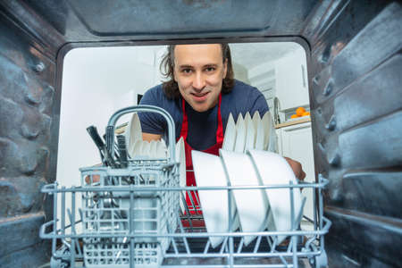 Man look at dishes and plates inside dishwasherの写真素材