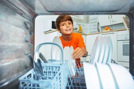 Child smiling take plates from dishwashing machineの写真素材