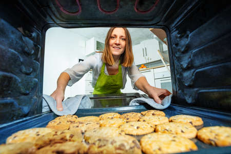 Woman take tray with baked cookies out of the ovenの写真素材