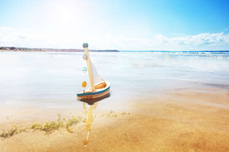 Little sail toy ship in the paddle on sea beachの写真素材