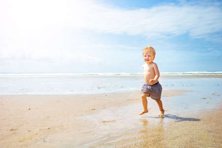Cute child boy run fast on the sand sea beachの写真素材