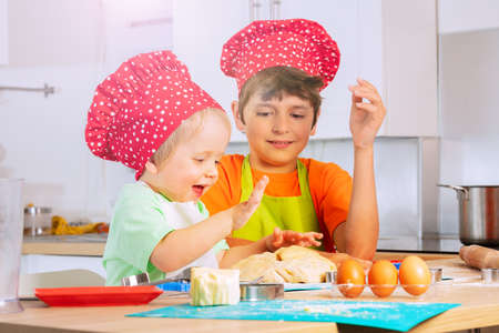 Two children crumble dough using hands at kitchenの写真素材