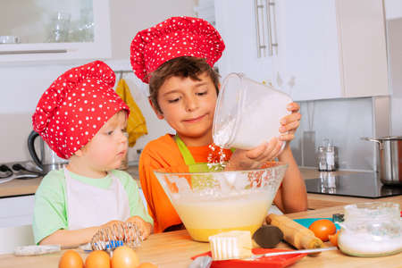 Boy add flour to the mixing bowl cooking cookiesの写真素材