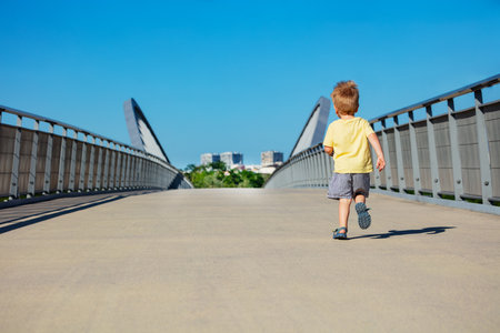 Blond toddler boy run away on a path walk in parkの写真素材