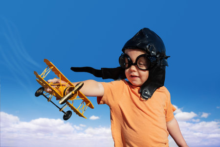 Boy with toy model of a plane wearing aviation hatの写真素材