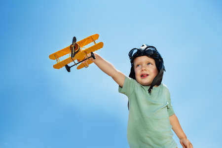 Portrait of a boy with airplane toy over blue skyの写真素材