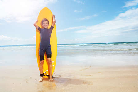 Boy pose stand with surfboard on a sand sea beachの写真素材