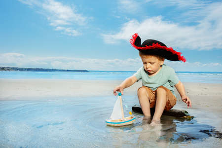 Little pirate play with sail boat in the puddleの写真素材