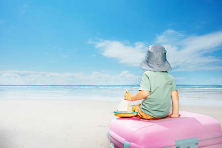 Nice sailor boy on baggage suitcase with toy boatの写真素材