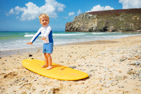 Blond toddler boy already practicing on surfboardの写真素材